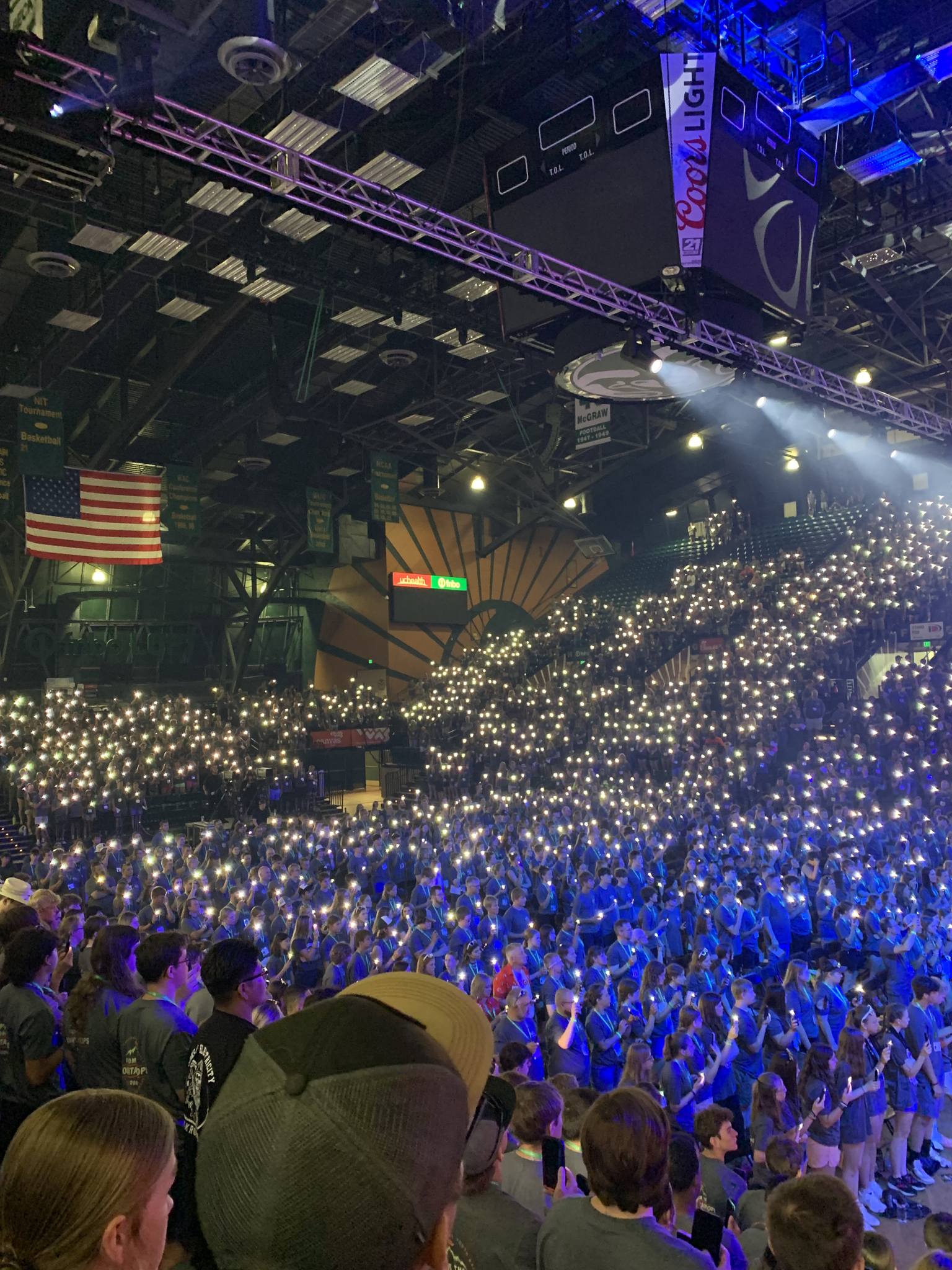Youth gathering — a large crowd of young people with phone lights raised in worship